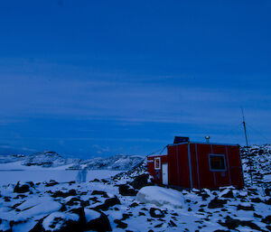 Evening photo of Watts hut with what appears to be 2 ghostly figures outside the hut