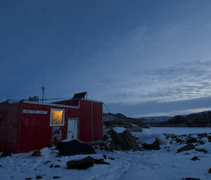 Evening photo of Watt’s hut with inside lights on