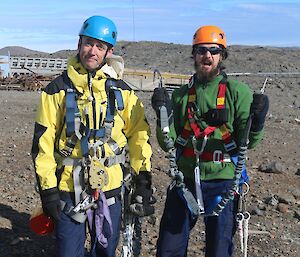 Two expeditioners dressed to climb an antenna with harnesses and hard hats
