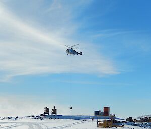 Helicopter about to place the large water container on the heli pad