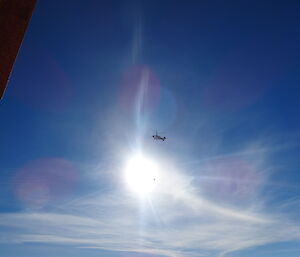 Large helicopter high above slingloading a large plastic container