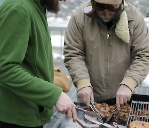 Two expeditioners cooking a BBQ outside on the balcony