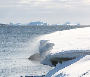 Snow blowing over an ice edge into the water