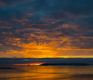 Brilliant and bright sunset across Davis station harbour — orange and red in colour