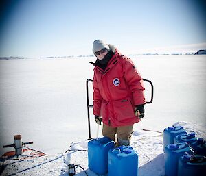 Expeditioner standing next to blue water containers