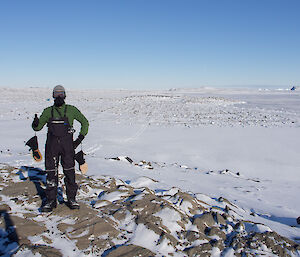 Expeditioner standing on high ground background of ice and rock