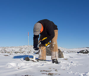 Expeditioner dropping tape measure into tube to measure water depths