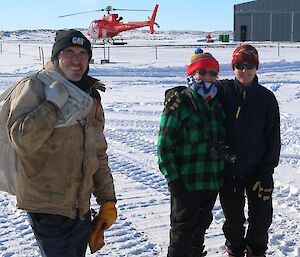 Three expeditioners and a red helicopter