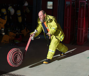 Expeditioner dressed in fire fighting gear rolling a fire hose