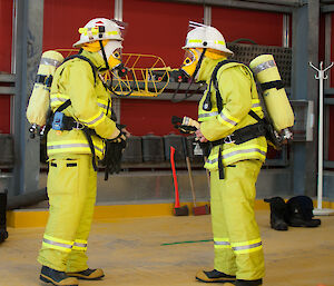 Two expeditioners in fire fighting gear checking each have the right gear on