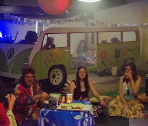 Expeditioners eating dinner sitting on the floor and in the fake Kombi van