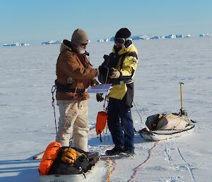 Expeditioners on the sea ice writing ice depth into log