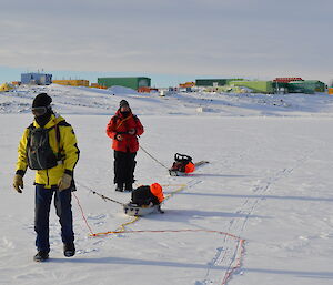 Two expeditioners on the sea ice roped together pulling sleds