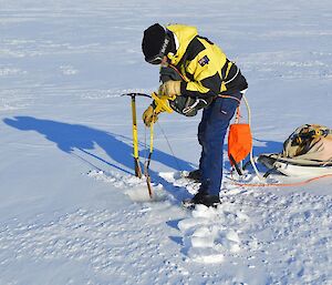 Expeditioner lowering a tape measure into the hole