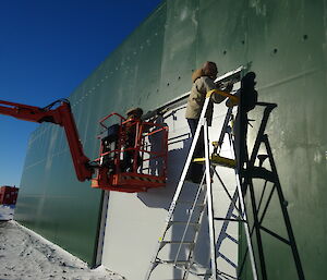 Two expeditioners intalling a large roller door on a new shed