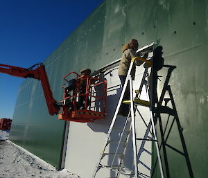 Two expeditioners intalling a large roller door on a new shed