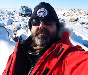 Expeditioner taking a self photo with blue hagglund in the background