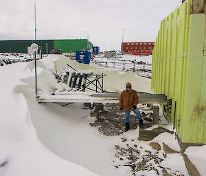 Expeditioner standing next to a building and a large wall of snow