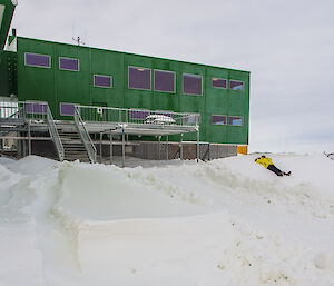 Expeditioner lying on a snow slope outside the living quarters