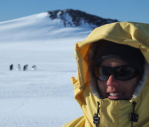 Close up photo of expeditioner with adelie penguins in the background