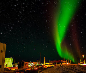 green aurora australis over station buildings