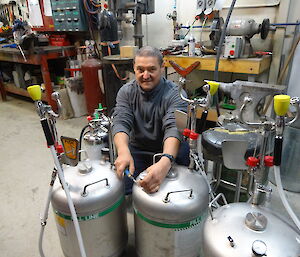 Expeditioner kneeling beside silver tanks