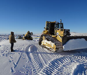 Caterpillar dozer pulling vehicles out of heavy snow