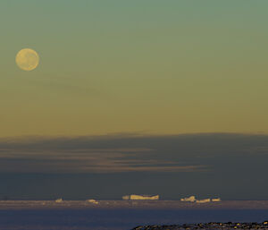 Full moon over the sea ice and bergs