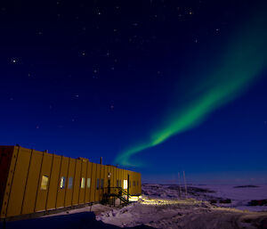 Green aurora over a large yellow building