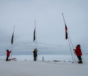 Three expeditioners raising the NZ, Australian and Aboriginal flags