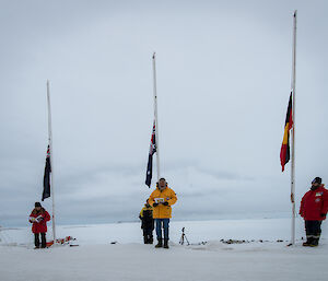 Expeditioner standing alongside raised flags addressing small community