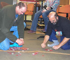 Two expeditioners on the floor gathering their chips from Two-Up game