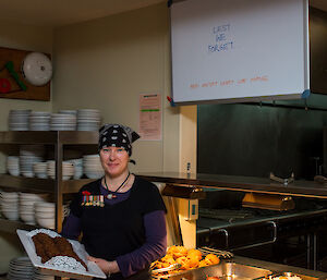 Female station chef holding tray of ANZAC biscuits