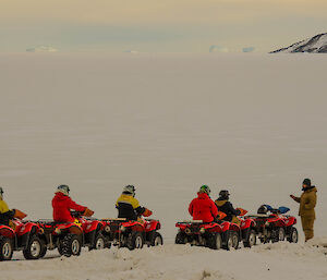 Expeditioner standing next to line of quads and riders