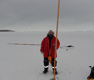 Expeditioner standing next to cane on sea ice