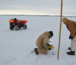 Expeditioner kneeling on sea ice with tape measure