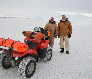 Two expeditioners standing next to a quad bike on the sea ice