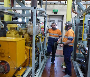 Two expeditioners standing alongside generators