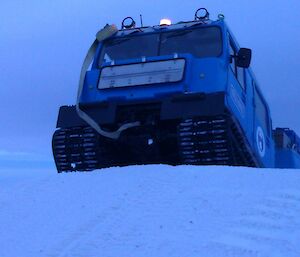 Blue Hägglunds driving over a steep slope