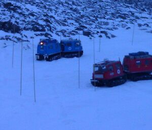 Red and blue Hägglunds driving through marked bamboo canes