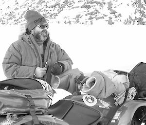 Black and white photo of expeditioner standing next to quad bike