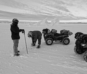 Black and white photo of expeditioners drilling sea ice