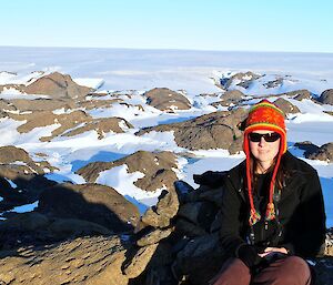 Expeditioner sitting on rocks, background of rocks and snow