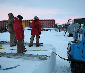 Three expeditioners looking at how best to recovery hagglund from ditch