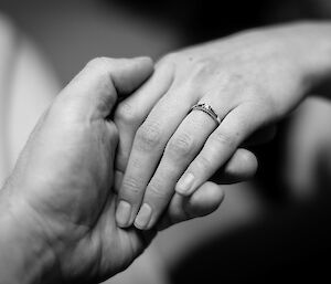 Close up of two people holding hands showing an engagement ring
