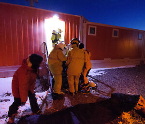 Group of expeditioners in fire fighting gear assist with patient