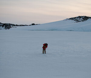 Photo of expeditioner on the sea ice drilling ice depth