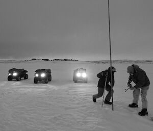 Black and white photo of two expeditioners measuring sea ice depth