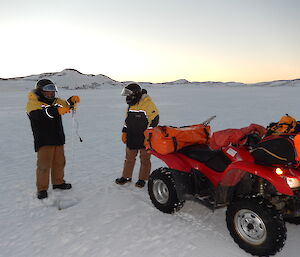 Two expeditioners on sea ice measuring ice depths