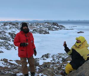 Two expeditioners on an island holding up chocolate
